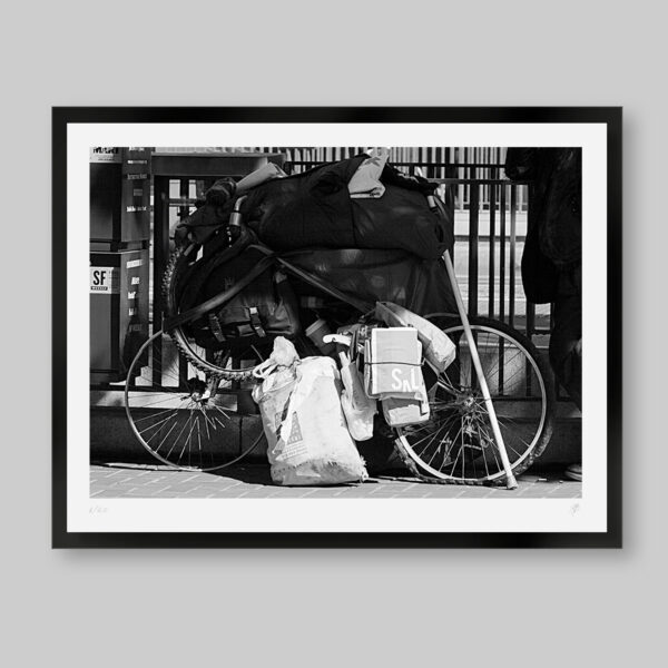 Fotografía artística en blanco y negro. Titulo: All you need. Bicicleta llena de cosas con una llanta desinflada y la otra solo el aro. Se puede interpretar que las cosas aunque parecen sin valor son todo para el dueño.
