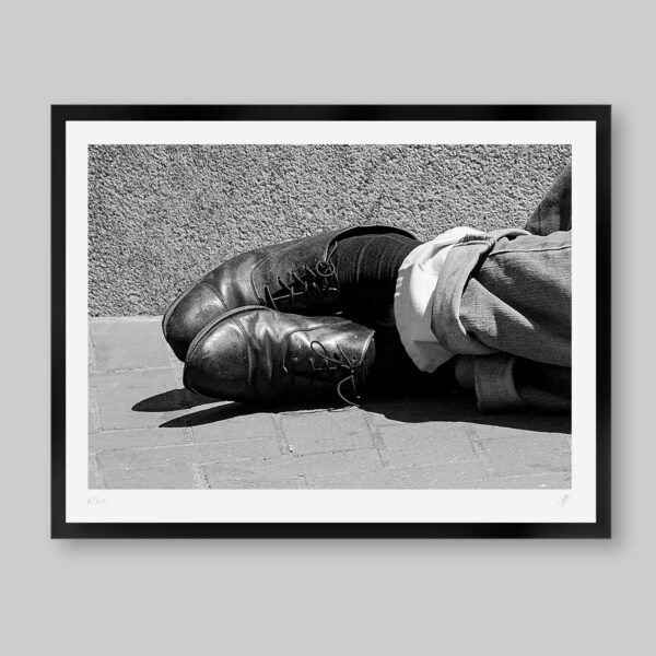 Fotografía en blanco y negro. Titulo: Sleeping shoes. Acercamiento a un par de zapatos de vestir elegantes gastados y soñadores, de alguien que esta durmiendo en el piso.