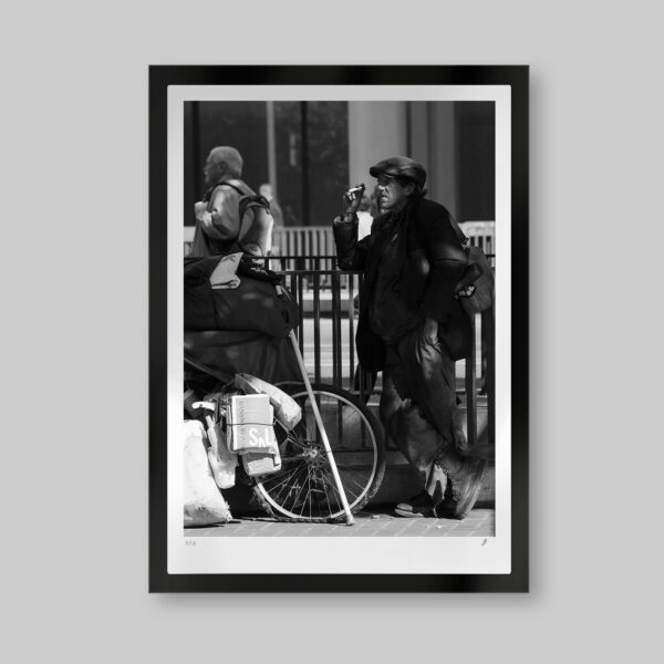 Fotografía artística en blanco y negro. Titulo: The joy of living. Hombre atemporal fumando en la calle con su bicicleta llena de cosas sin aire en las llantas.